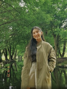 Photo of young woman in green coat with marsh in the background