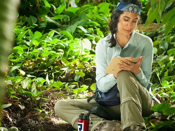Girl seated in jungle area taking notes
